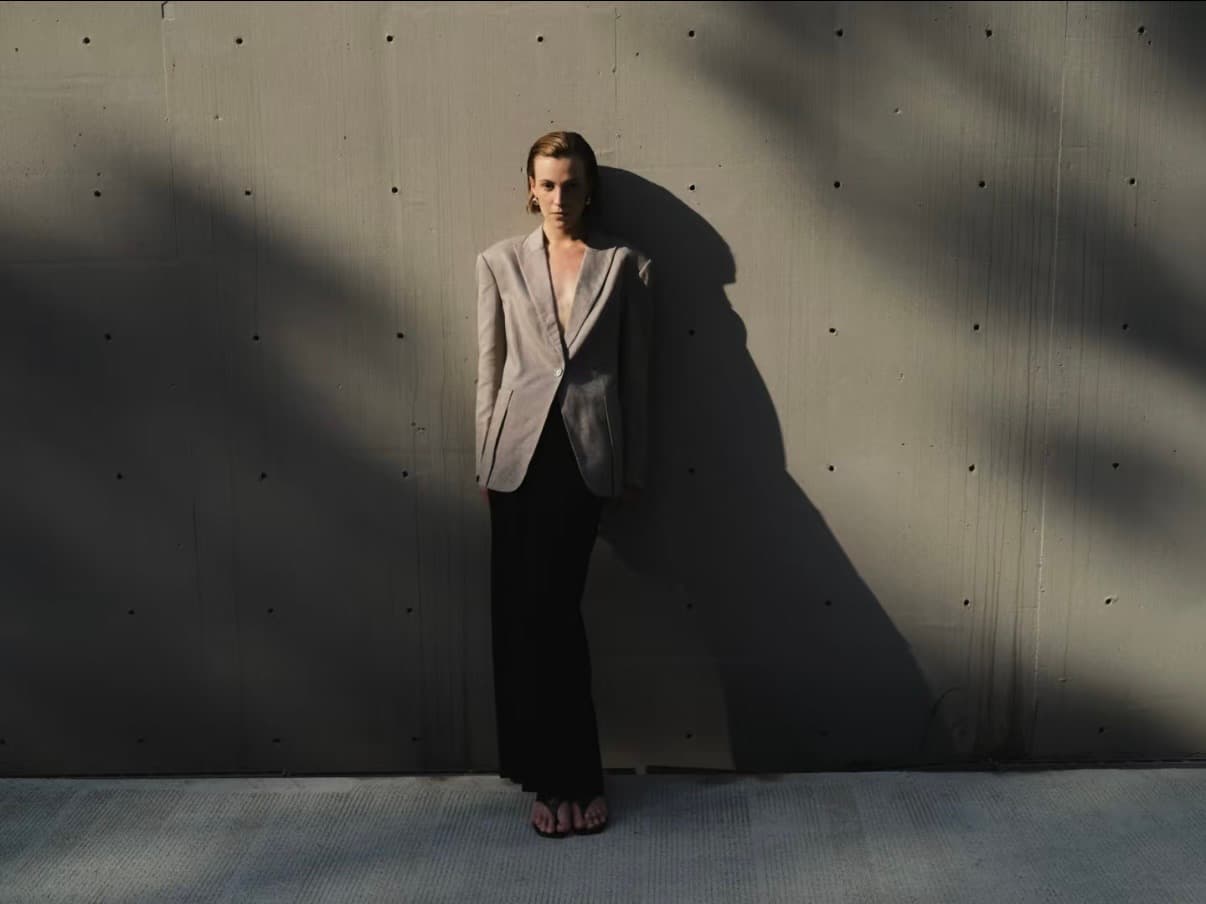 Gentle Authority model in tailored jacket against a concrete wall