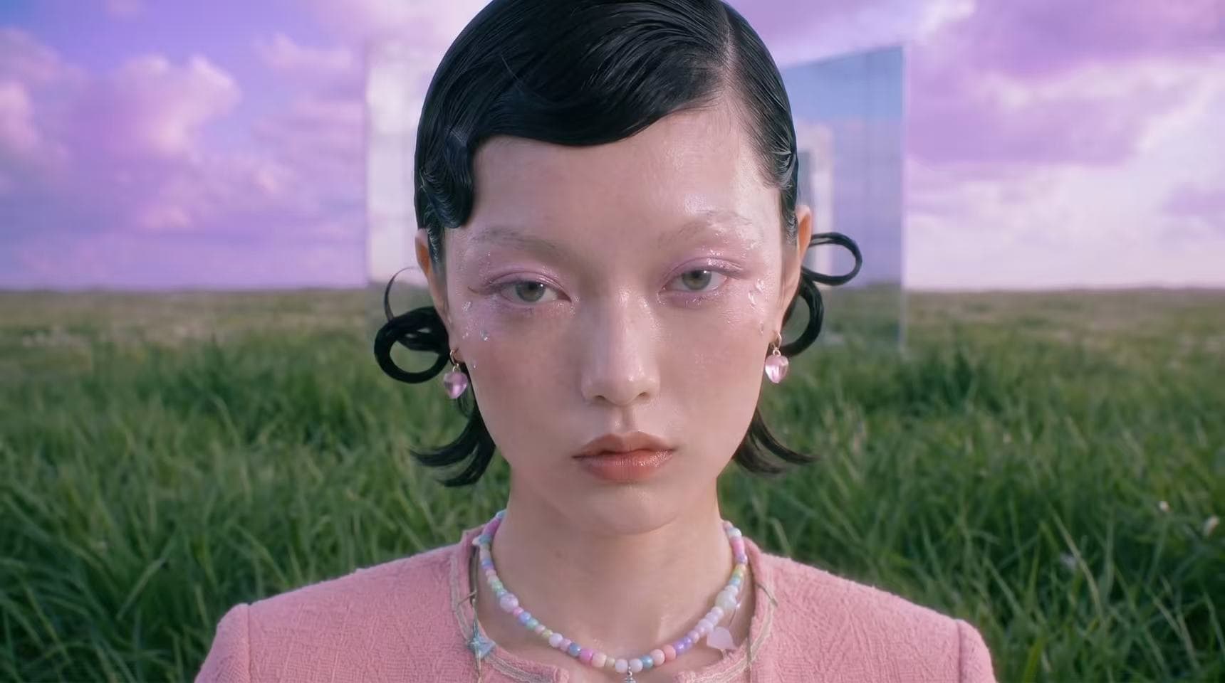 Close portrait of a model in a field with mirrored architecture behind her